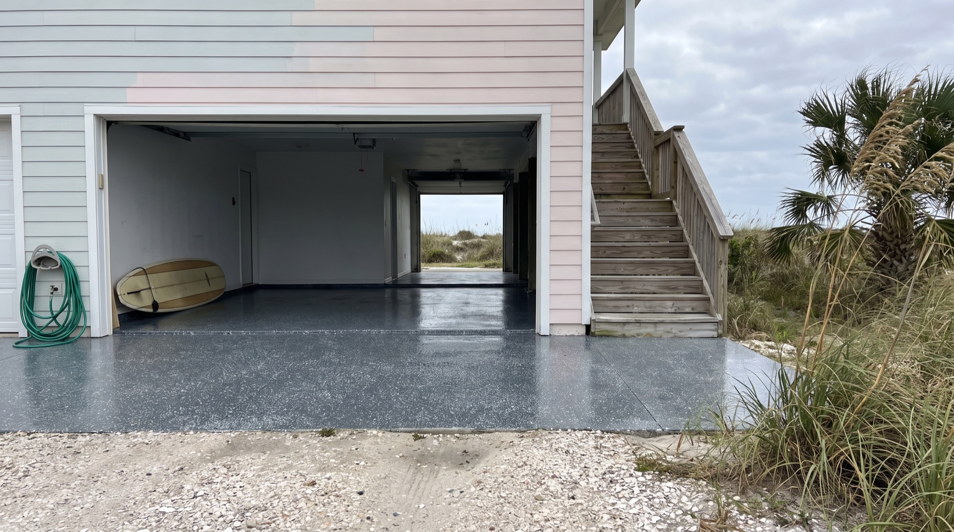 Open garage with a glossy charcoal flake epoxy floor at a raised coastal home on Anastasia Island, St. Augustine Beach